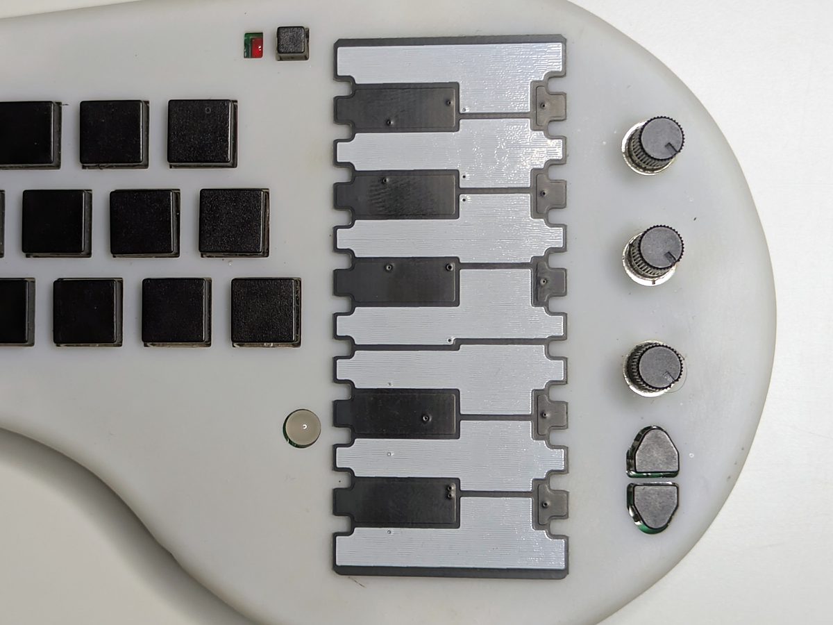 The Piano Keys harp plate fitted to a minichord: an octave of silver and black keys on its side, beside the chord buttons and knobs
