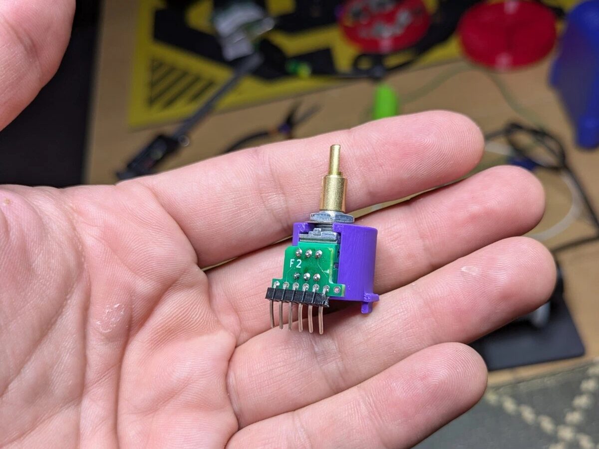 The new dual potentiometer on its green adapter board and purple housing, held in a hand